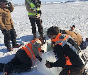 The tide gauge team moving ice blocks that have been cut by the chainsaw