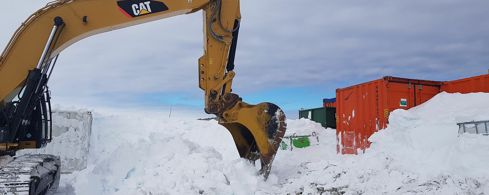 An excavator digging containers out of the winter snow at Casey