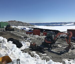 An excavator surrounded by shipping containers at main remediation site at Casey