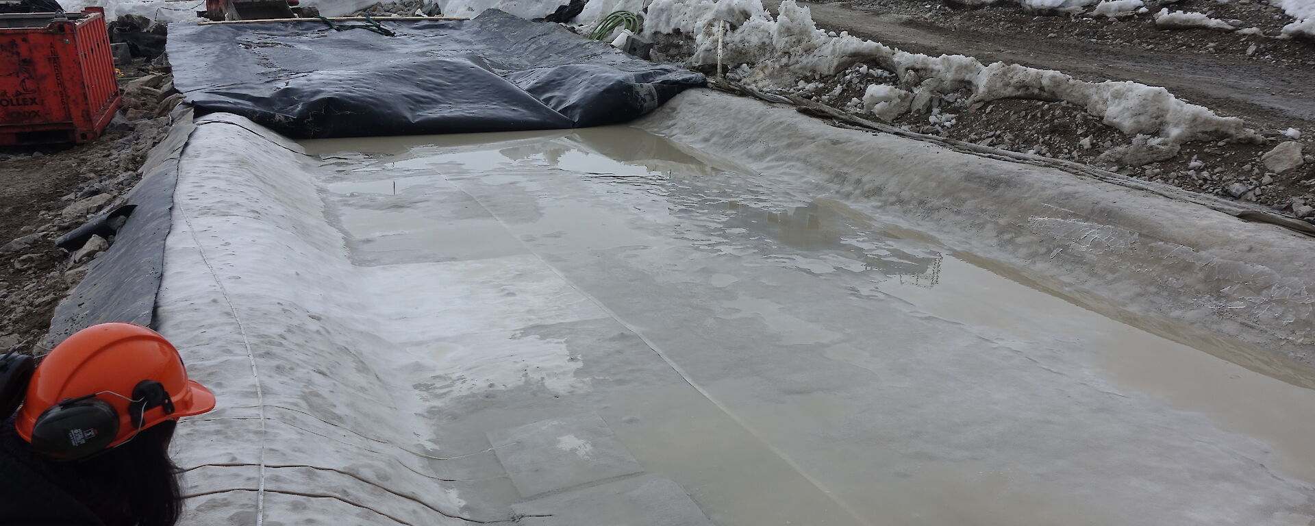 The biopile barrier system showing the black high density polythene primary barrier and the beige geosynthetic clay liner (GCL) as the secondary barrier below