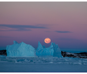 Spectacular Antarctic moon and ice berg