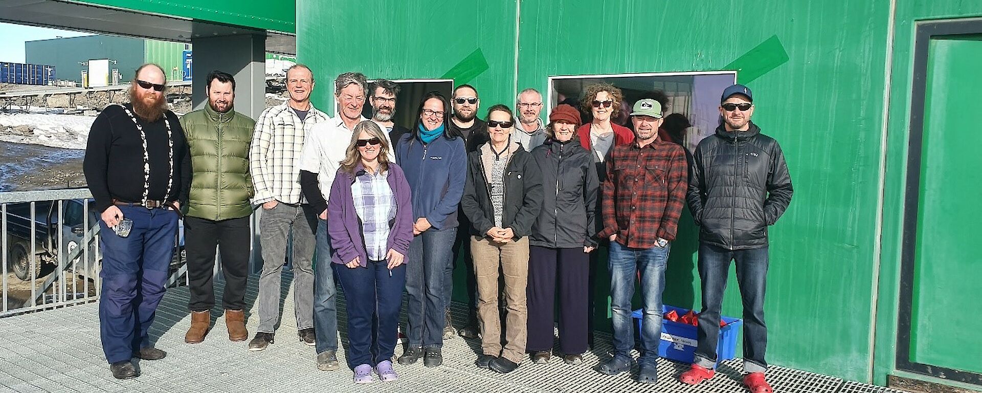 14 of the Davis Aerodrome Project expeditioners pose on the station’s living quarters deck