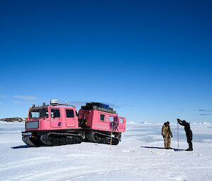 Dan and Mike drilling a fast ice way-point in front of their pink Hägglunds vehicle