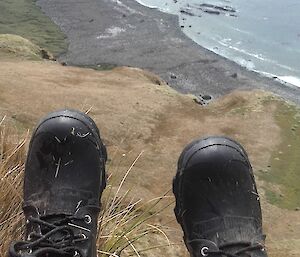 Sitting on the top of a ridge looking down the west coast on a field trip — boots in the foreground