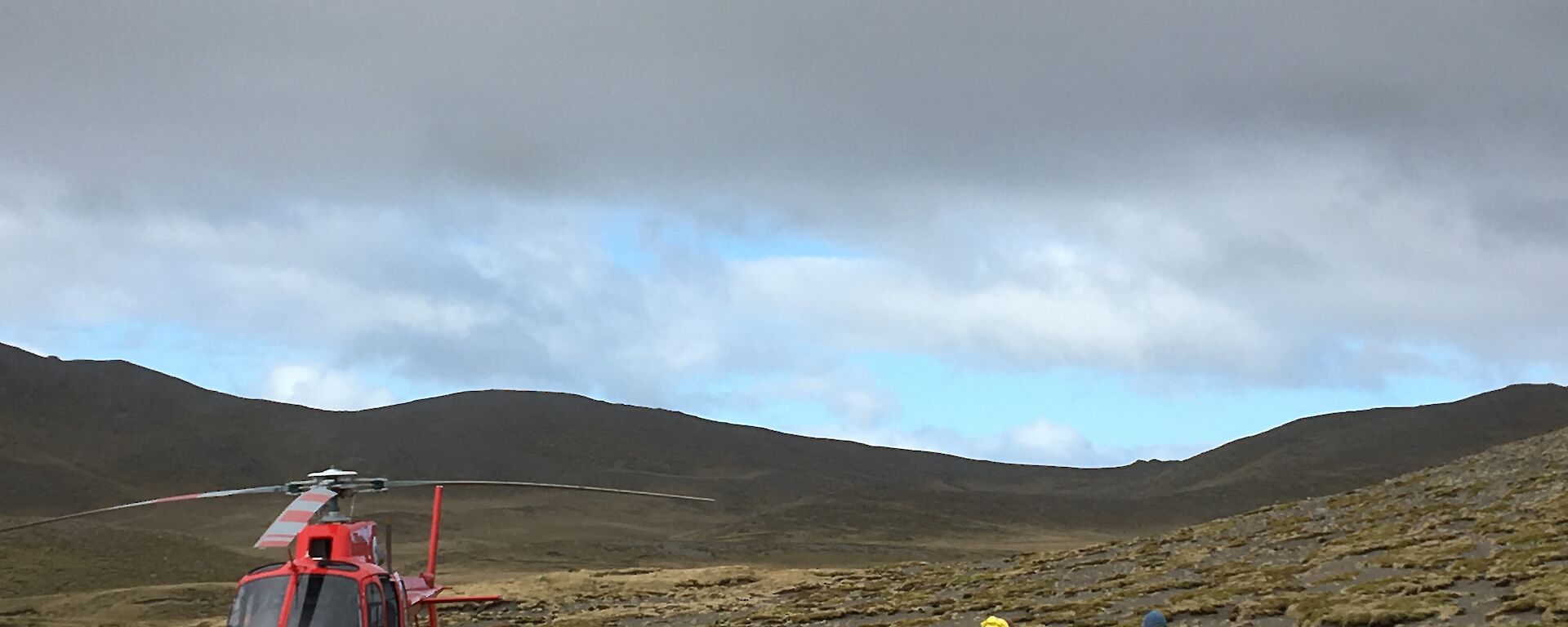 Two people are restocking a yellow tub with a red helicopter nearby