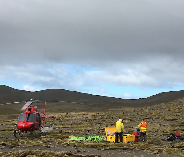 Two people are restocking a yellow tub with a red helicopter nearby