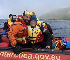 two people hug and smile while on a red boat