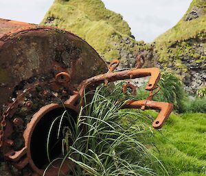 A rusted metal structure lays on its side near some rocky outcrops