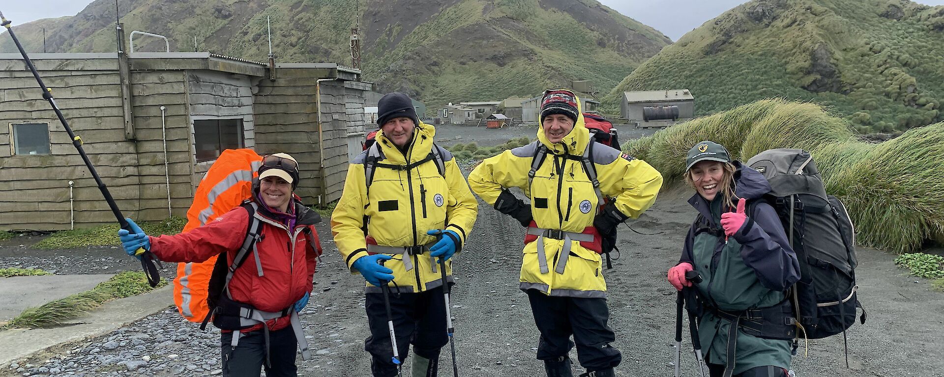 four people wear hiking gear ready to go on a hike