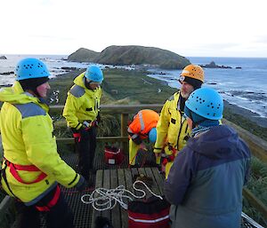 5 people are getting ropes ready to set up a rescue rigging system