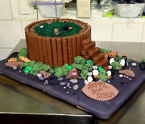 A round birthday cake is surrounded by penguins and elephant seals