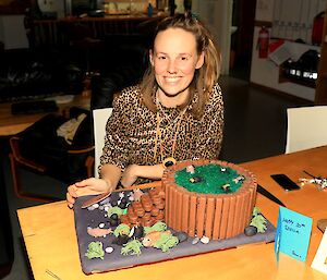 A woman sits in front of the penguin and seal themed birthday cake