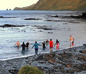 nine people step into the calm waters of a bay