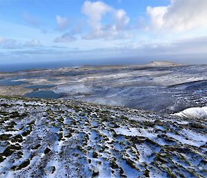 A vast plateau with a dusting of snow, blue sky and clouds