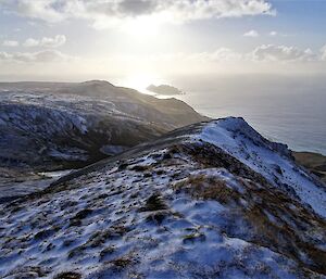 a snow dusted ridge with a view of the southern ocean in the distance