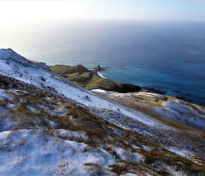 a rocky outcrop called the Nuggets is viewed from the top of a dust covered ridge with the Southern ocean to the horizon