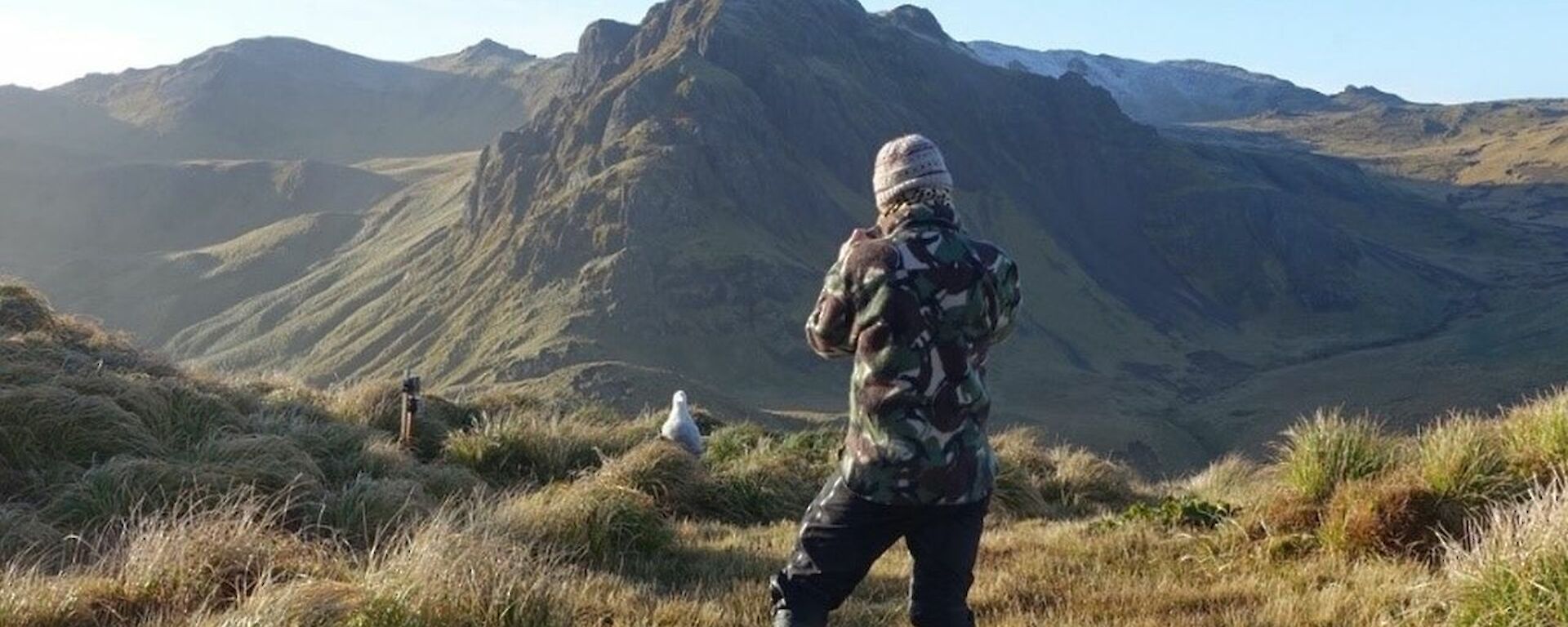 A woman in camouflage jacket is standing in front of a wandering albatross