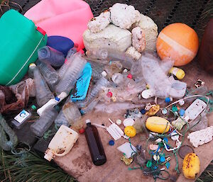 A collection of coloured plastic junk for example, buoys, ropes, a block of styrofoam and more bottles
