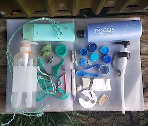 A variety of plastic items in shades of blue and green including toothbrushes and shampoo bottles