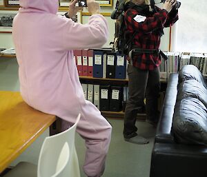 A man in a rabbit costume is filming a woman wearing a ranger costume sneering at the camera
