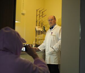 A man in a white lab coat is being filmed by a man in a rabbit costume