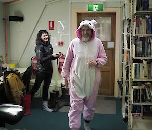 A man in a rabbit costume walks away from a woman holding a camera