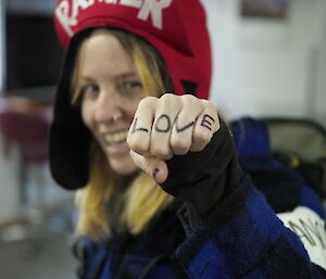 A woman in a Ranger costume shows her knuckles with LOVE written across them to the camera