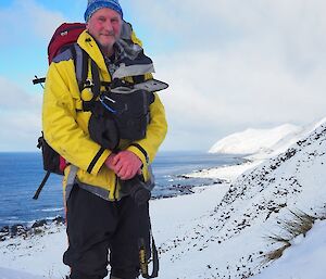 A man in a yellow jacket stands in the snow