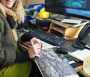 A woman is counting penguins from a coloured photograph