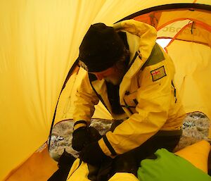 A man is inside a yellow tend attending to a patient’s ankle