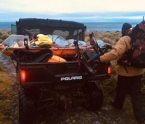 A patient in a stretcher is being transported on the back of a Polaris vehicle
