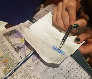 A person rubs a pencil over a piece of paper