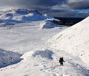 Snowy landscape with a hiker walking knee deep in snow.