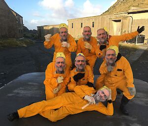 a group of people in orange jump suits hold masks in front of their faces