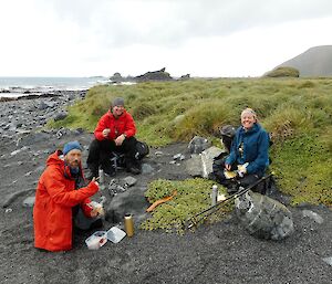 three expeditioners eat lunch in field at MI