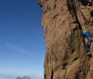 A man climbs the final rock section of the mountain