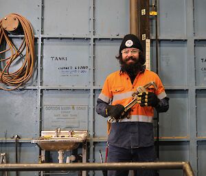 Man with spanner in front of water tank