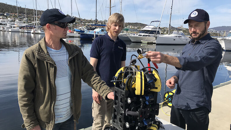 Dr Jonny Stark (left), SOSub Director Kelsey Treloar, and Dr Glenn Johnstone, with the ROV, at a wharf in Hobart.