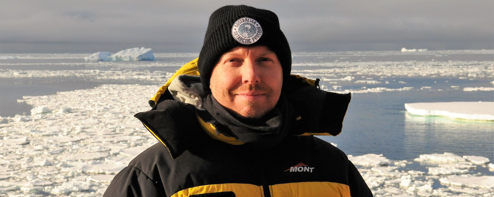 Captain Paul Clarke on the deck of the Aurora Australis with sea ice behind.