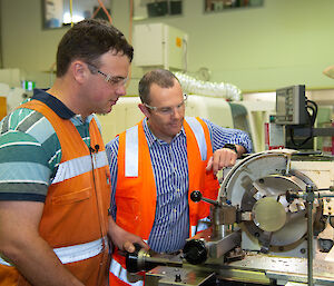 Two instrument technicians monitor construction of an ice core drill head.