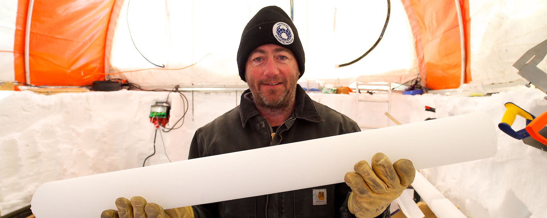 Dr Mark Curran holds an ice core inside a drill tent in Antarctica
