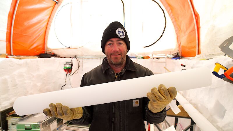Dr Mark Curran holds an ice core inside a drill tent in Antarctica.