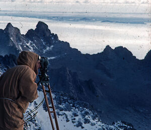 Syd Kirkby taking a sighting with a theodolite from Rumdoodle Peak.