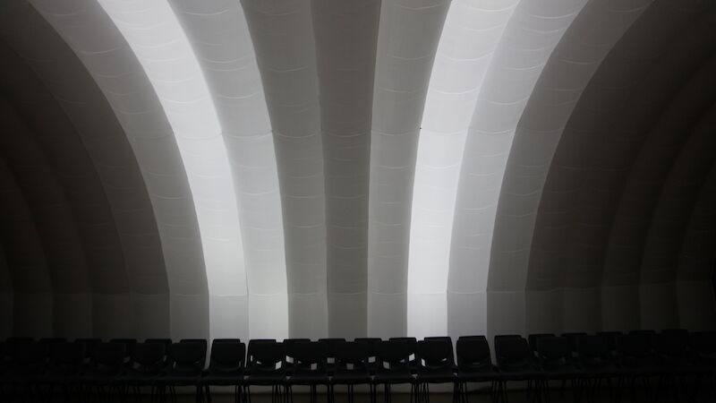 A row of chairs beneath an inflatable white performance space.