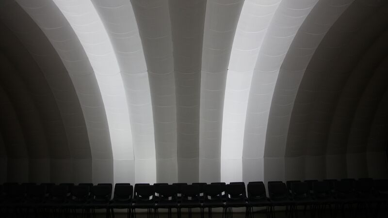 A row of chairs beneath an inflatable white performance space