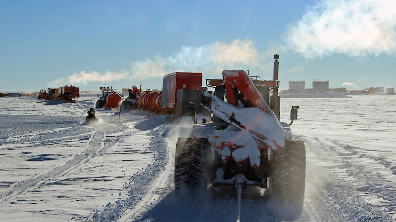 A train of tractors pulling fuel containers.