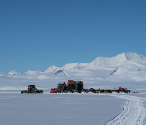 A tractor traverse in Antarctica with mountains in the distance.