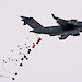 Pallets of supplies attached to parachutes drop from the tail end of a C-17A aircraft.