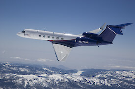 A Gulfstream V aircraft flying over mountains.