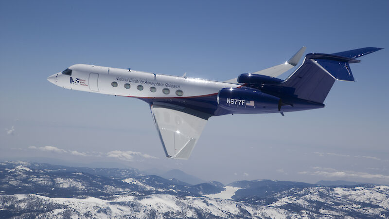 A Gulfstream V aircraft flying over mountains.